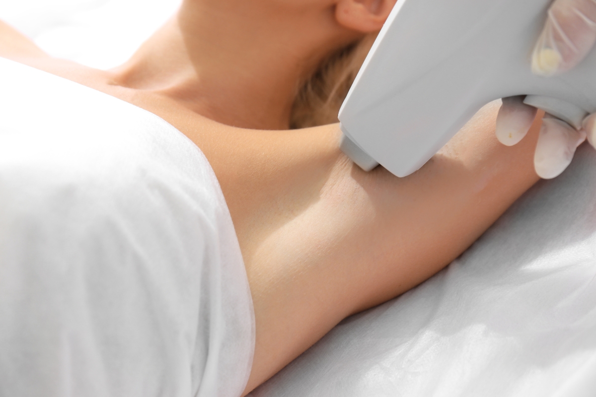 Hair reduction treatment being applied to someone's underarm, by a medical professional using a laser machine.